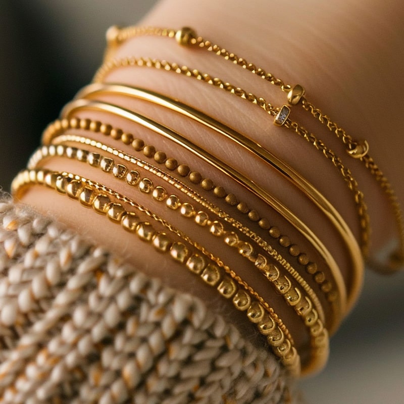 Person’s hands and wrists adorned with various gold jewelry pieces